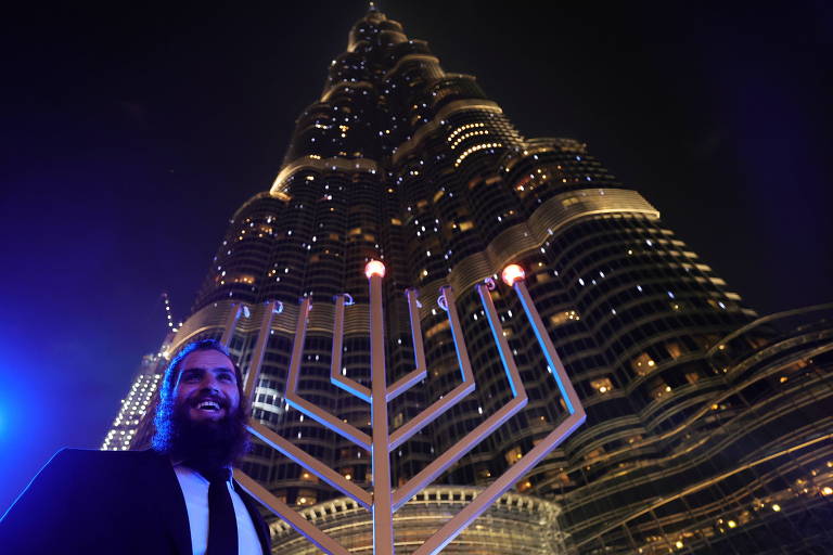 Um homem posa ao lado de menorá gigante durante celebração do Hanukkah em Dubai, nos Emirados Árabes Unidos