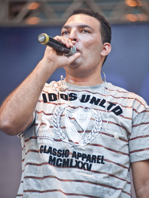 homem de cabelo curto e camiseta listrada segurando um microfone