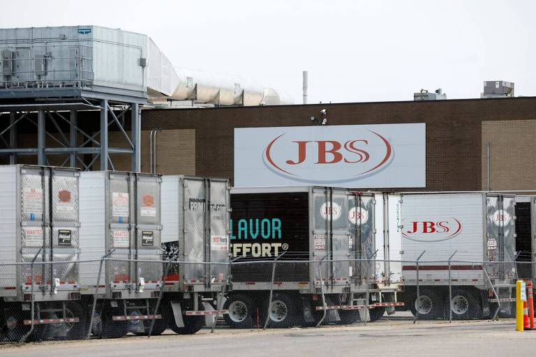 Caminhões estão parados em um estacionamento da fábrica da JBS