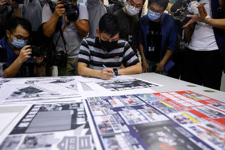 Cercado por fotógrafos, o editor-executivo do Apple Daily, Lam Man-chung, analisa a última edição da publicação 
