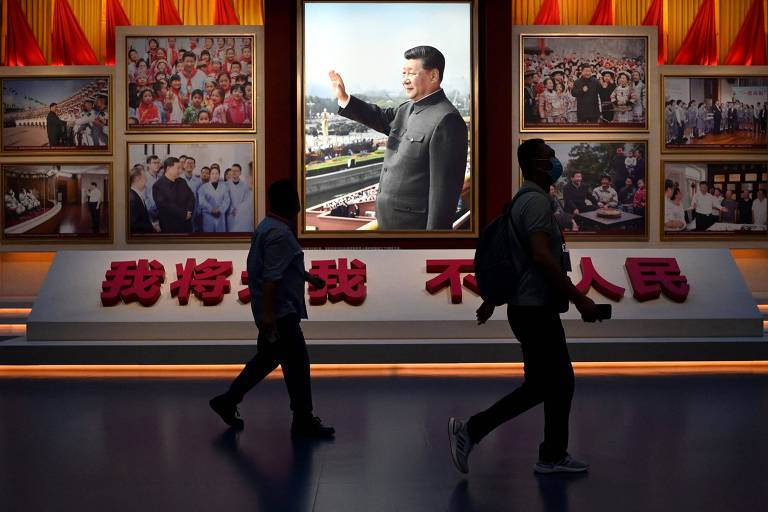 Homens passam em frente a imagem do atual dirigente da China, Xi Jinping, no museu dedicado ao Partido Comunista, em Pequim
