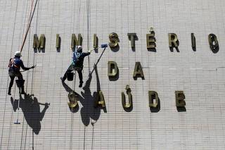 Funcionários limpam fachada do prédio do Ministério da Saúde