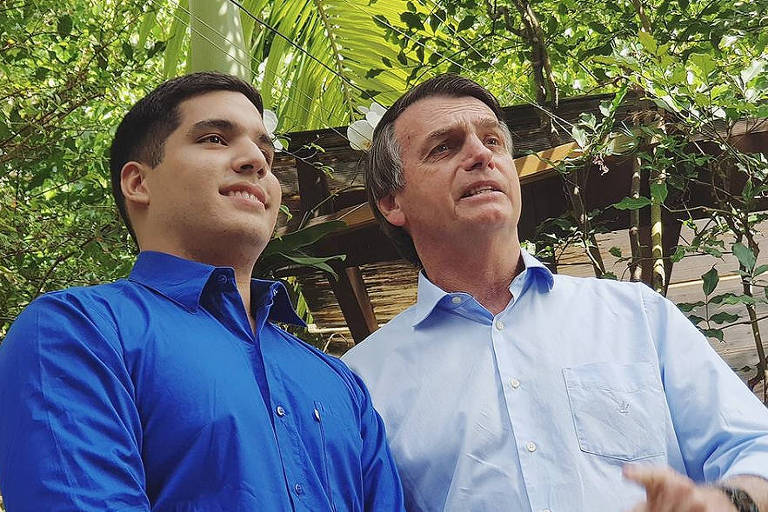 Um homem jovem, de camisa azul, ao lado de Bolsonaro