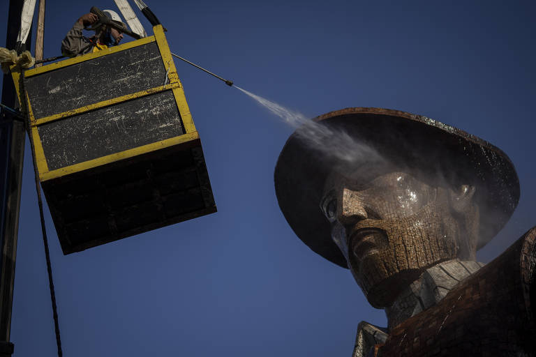 homem em grua laca com água cabeça da estatua de borba gato