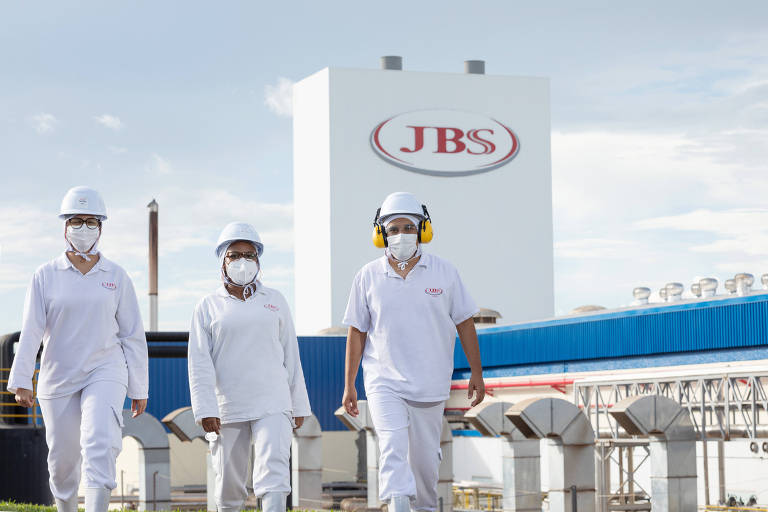 Funcionários da JBS caminham em frente a uma fábrica da companhia