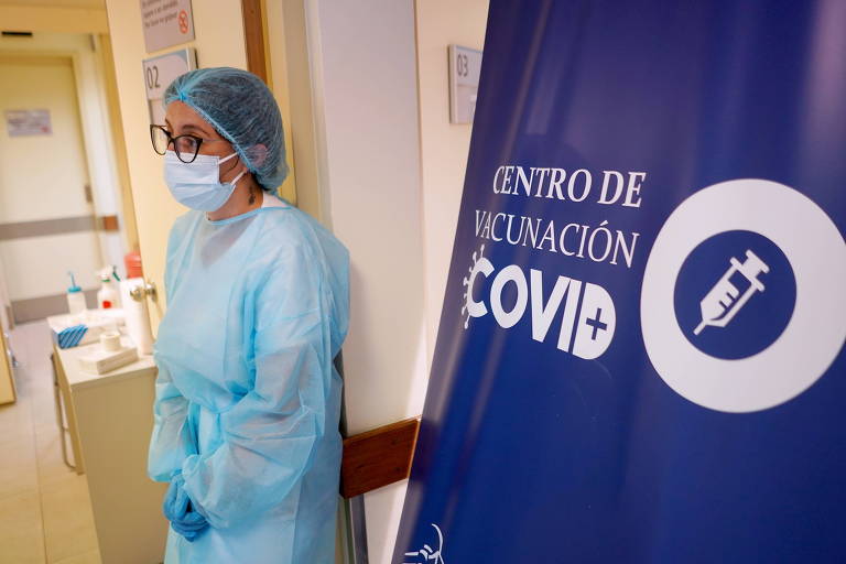 Profissional da saúde de máscara e roupa especial em centro de vacinação em Montevidéu