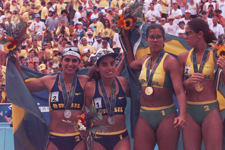 Quatro mulheres de biquíni, uniforme do vôlei de praia, em pódio