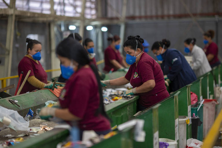 Mulheres com máscara PFF2 separam lixo reciclável em esteira 