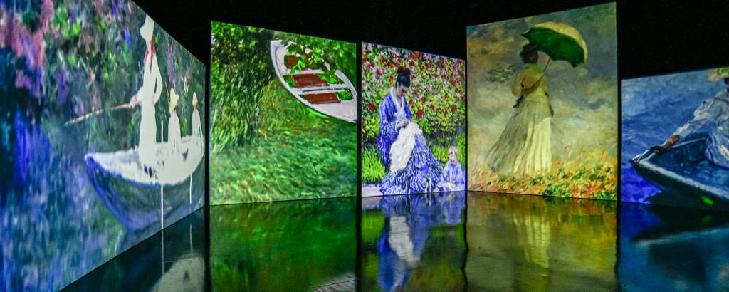 Em um ambiente escuro, cinco pinturas de Monet estão dispostas uma ao lado da outra, em telas digitais 