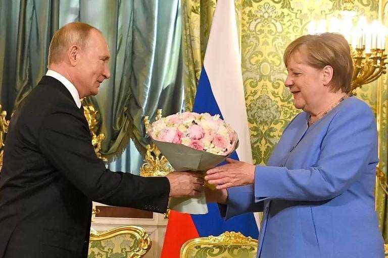 Putin dá flores a Merkel na última visita da alemã como primeira-ministra ao Kremlin, em Moscou

