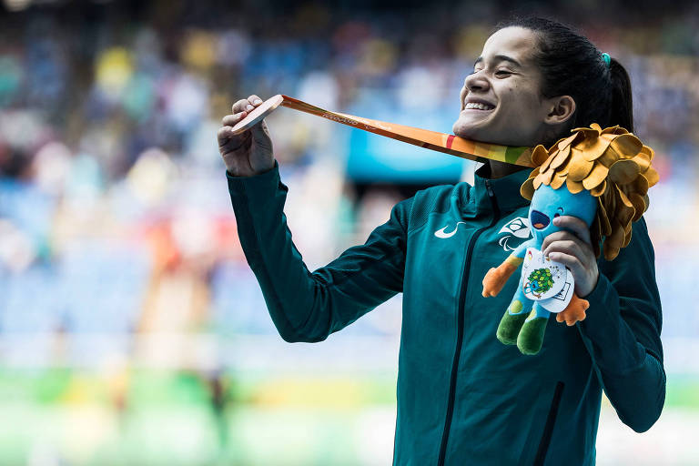 Verônica estica a medalha pendurada no pescoço e sorri 