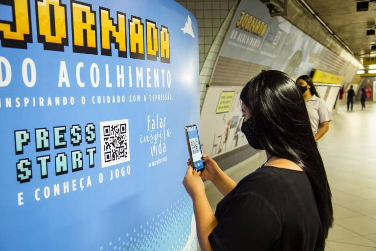 Passageira do metrô se prepara para brincar com o game da campanha Jornada do Acolhimento, na estação Paulista