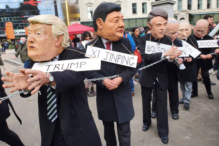 Ativistas com máscaras de líderes mundiais, acorrentados e apresentados como criminosos climáticos, desfilam durante protesto contra a crise climática, em Glasgow, na Escócia, em que acontece a COP26; estavam representados o ex-presidente dos EUA Donald Trump, o presidente chinês, Xi Jinping, Bolsonaro, o primeiro-ministro da Austrália, Scott Morrison, o líder russo, Vladimir Putin, o magnata da mídia Rupert Murdoch, e o premiê indiano, Narendra Modi.