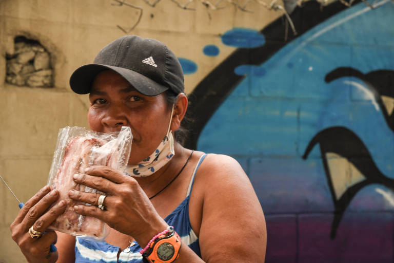 De boné, mulher cheira um pacote de bacon