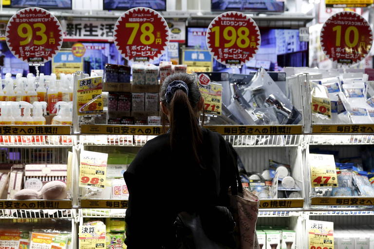 Consumidora observa preços em estabelecimento comercial nos arredores de Tóquio, no Japão
