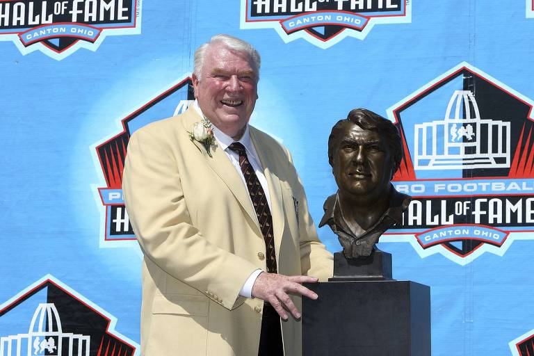 John Madden em frente a um busto de si durante cerimônia que o levou ao hall da fama do futebol americano, em 2006 