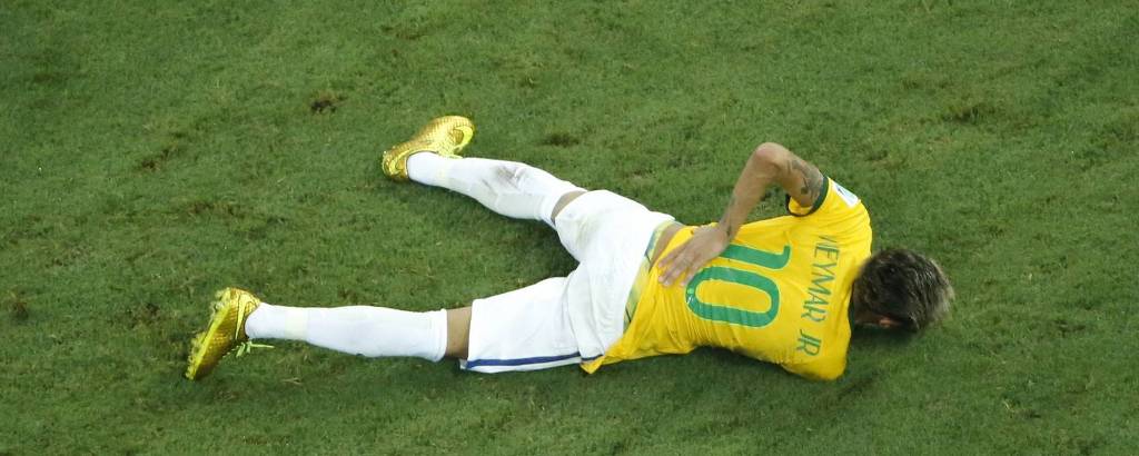 Neymar, camisa 10 às costas, caído de bruços no gramado do estádio Castelão, em Fortaleza, depois de ser atingido por Zúñiga, da Colômbia, em partida das quartas de final da Copa do Mundo; ele leva a mão esquerda às costas