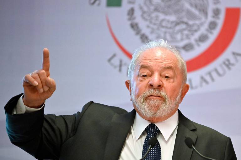 Homem gesticula durante discurso, com fundo azul 
