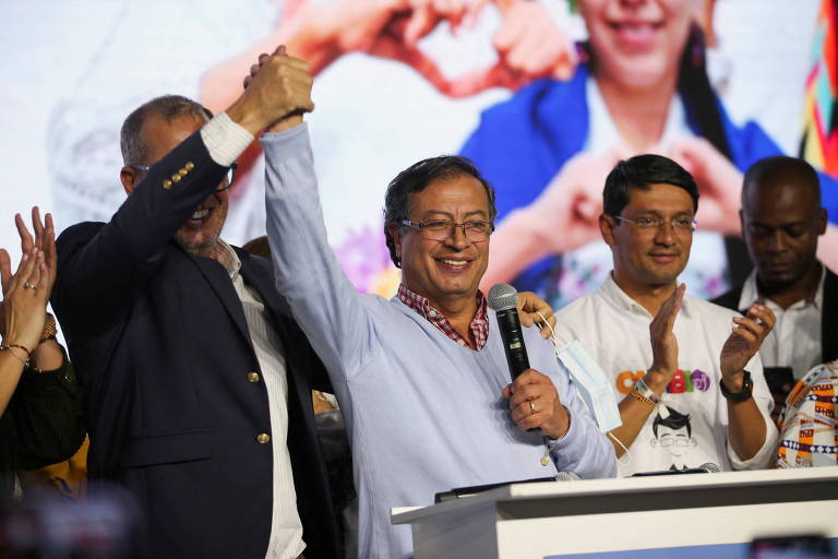 Em um palco, Petro segura microfone e dá a mão para um apoiador.