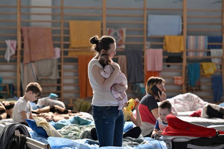 Mulher com bebê de dois meses nos braços em um abrigo em Przemisl, perto da fronteira da Polônia com a Ucrânia