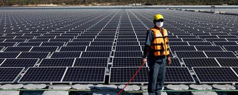A worker stands beside floating solar panels for the Sirindhorn Dam hydro-solar farm run by the Electricity Generating Authority of Thailand (EGAT) in Ubon Ratchathani on February 23, 2022. (Photo by Jack TAYLOR / AFP)