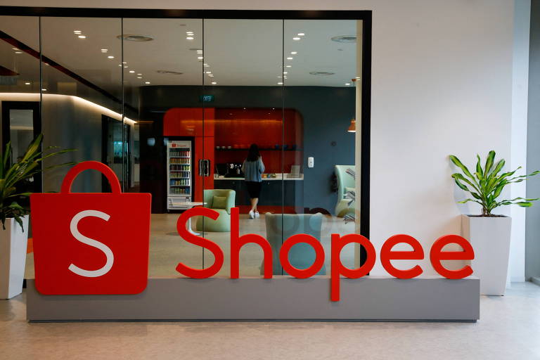 Imagem mostra uma foto do escritório da Shopee em Singapura, país onde a plataforma foi criada. É possível ver um espaço corporativo, e em destaque na imagem uma placa enorme com o logo da empresa na cor laranja.