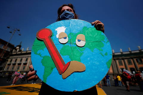 FILE PHOTO: A person holds a placard as climate activists including Extinction Rebellion and Fridays for Future stage a protest demanding more action whilst G20 climate and environment ministers hold a meeting in Naples, Italy, July 22, 2021. REUTERS/Guglielmo Mangiapane/File Photo ORG XMIT: FW1