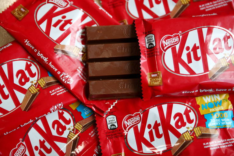 Imagem mostra várias unidades do chocalate Kitkat numa embalagem vermelha com a logo. Um deles está aberto no centro da foto.