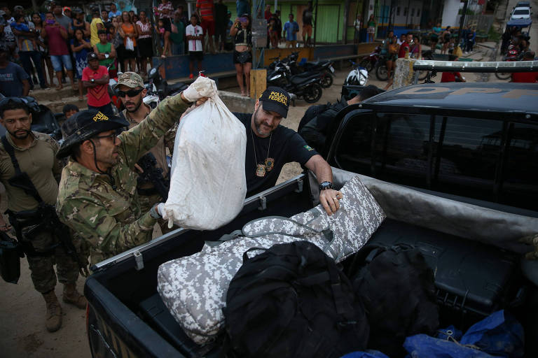 Homens colocam saco branco na traseira de uma caminhonete 