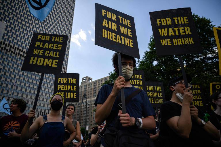 Jovens com máscaras seguram placas com mensagens como "pelo ar que nós respiramos" (em inglês)