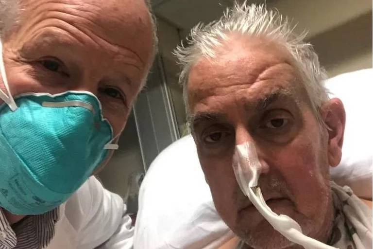 Imagem em close mostra o rosto de um médico, de máscara, e um paciente, posando para foto