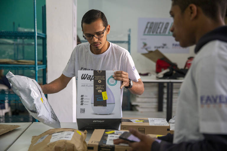 Francildo Phênnes Alves de Souza (esq.), coordenador do QG da Favela Llog em Paraisópolis, confere encomenda da Amazon feita por moradores da segunda maior favela de Sâo Paulo