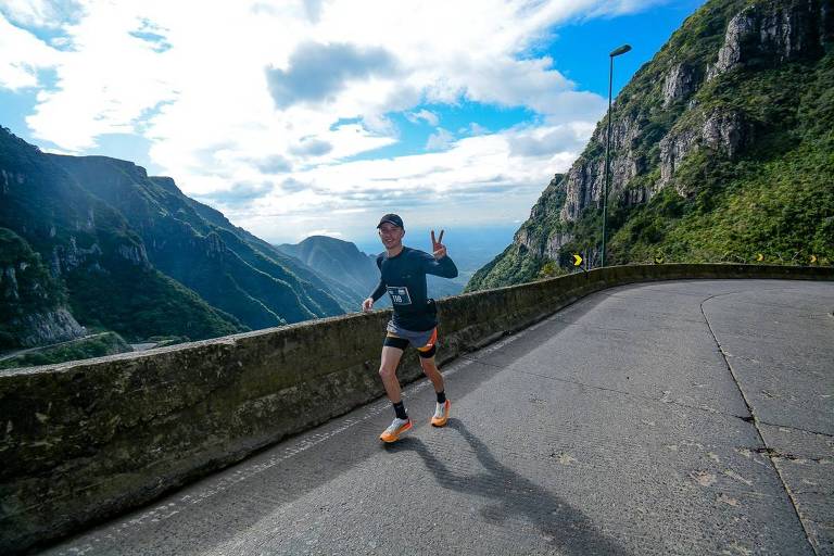 Atleta corre maratona em serra com montanhas ao fundo