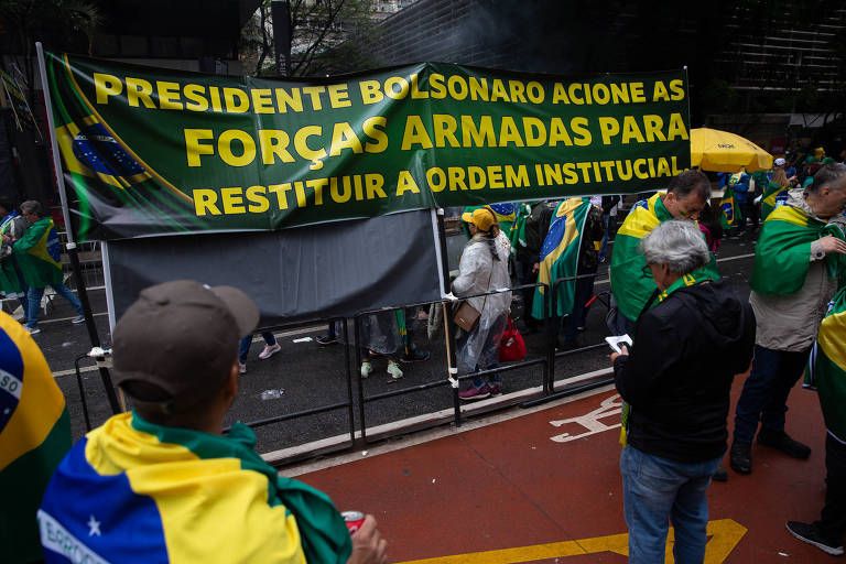 pessoas seguram cartaz que defende que o presidente Bolsonaro acione as forças armadas