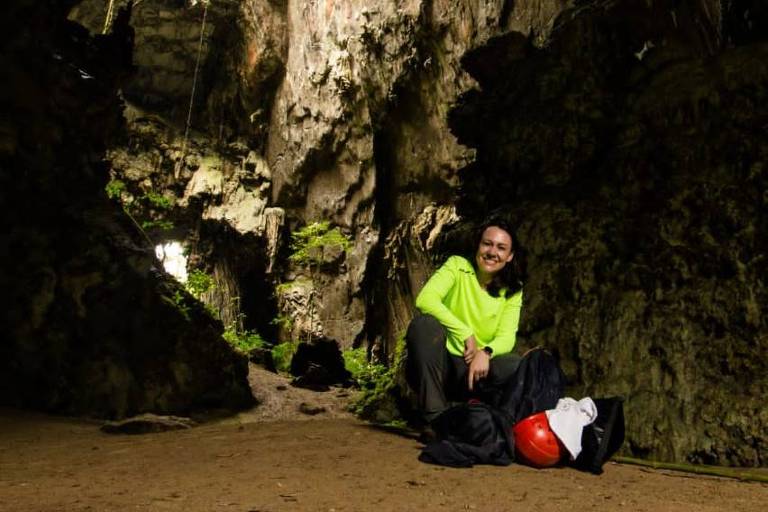 Mulher branca, agachada à entrada de gruta no Petar