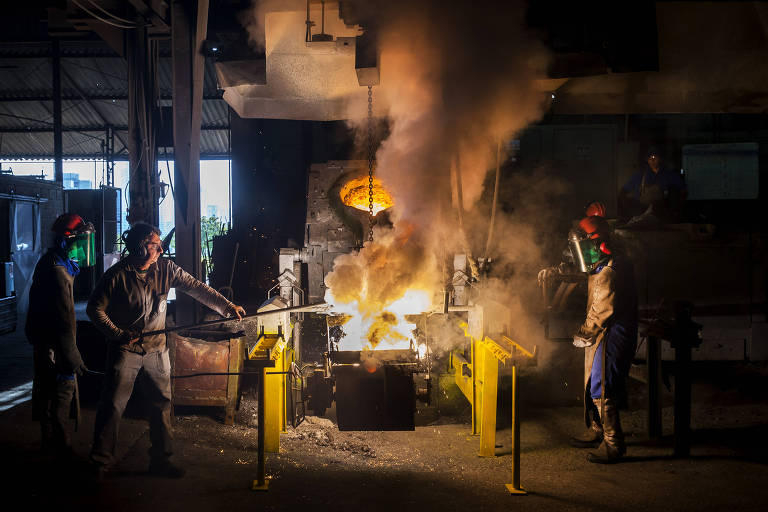 Operários controlam um dos fornos usados para derreter ferro e aço em indústria em Barueri