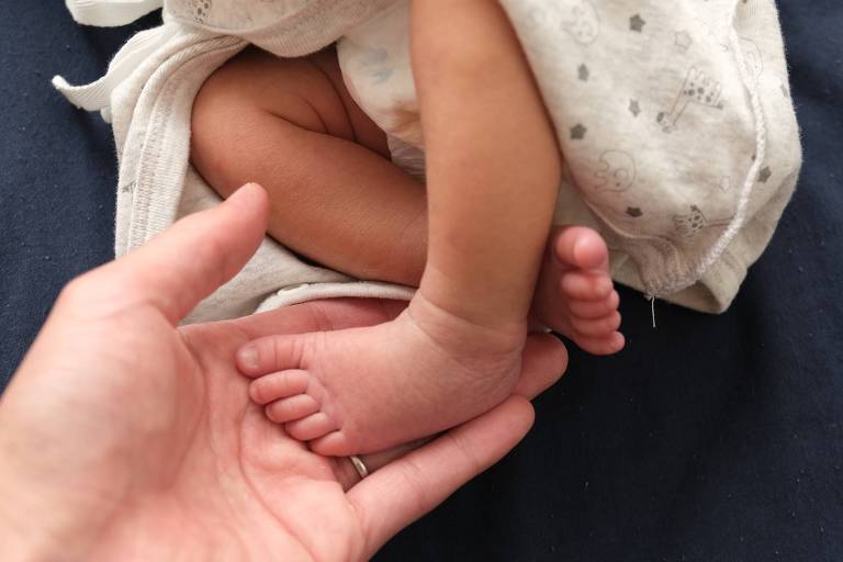 Close em uma mão segurando o pé de um bebê 