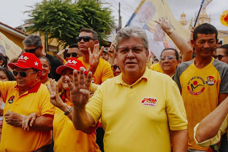 homem de amarelo caminha em campanha eleitoral na rua com apoiadores