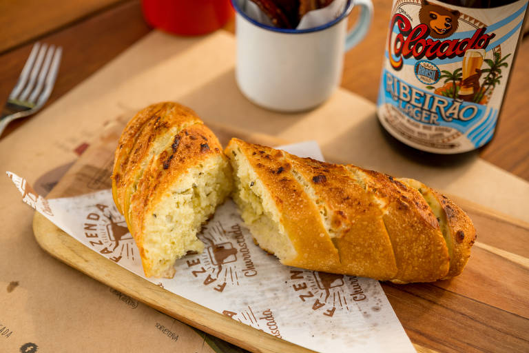 Pão de alho cortado em fatias sobre tábua de madeira