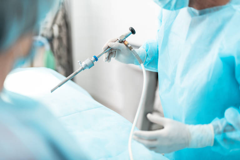 Close up of male hands in white sterile gloves holding laparoscopic instrument