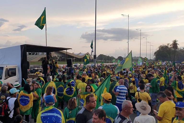 Manifestantes estão reunidos com bandeiras do Brasil e camisetas verde-amarelo em frente ao quartel-general do Exército, em Brasília
