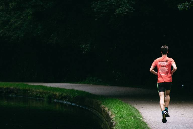 Homem corre em pista ao lado de rio