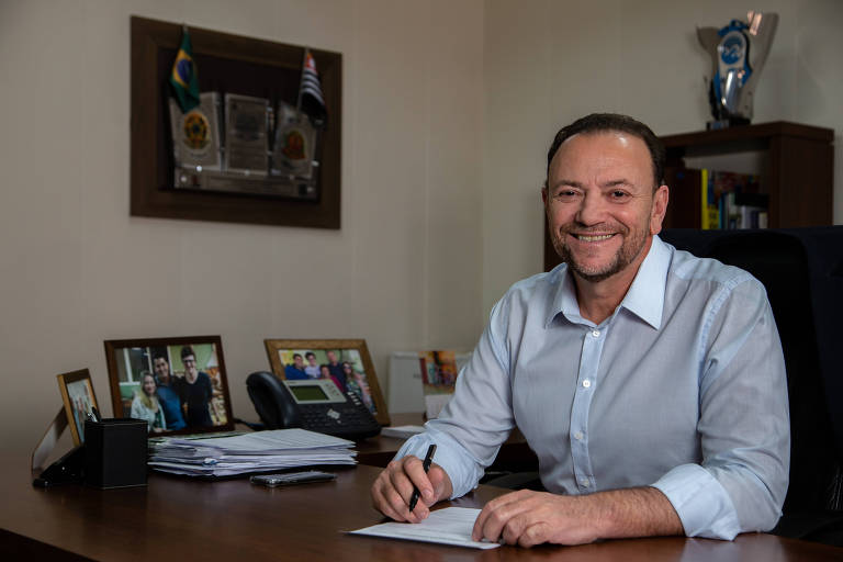 O prefeito de Araraquara, Edinho Silva (PT), sentado à mesa de seu gabinete com uma caneta na mão sobre um papel