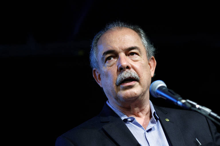 Foto mostra o coordenador dos grupos técnicos do gabinete de transição, Aloizio Mercadante, durante entrevista a jornalistas. Ele é um homem branco, grisalho, de bigode. Veste um terno preto e uma camisa clara. Está em frente a um fundo preto. 