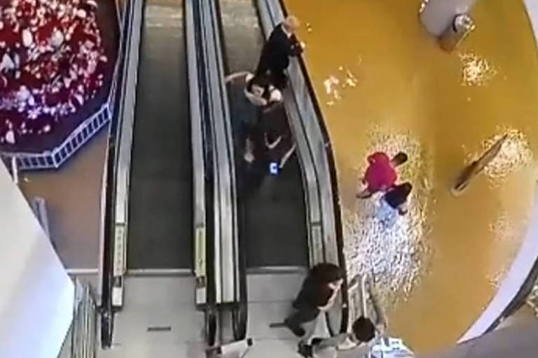 Consumidores descem escada rolante em direção a piso alagado