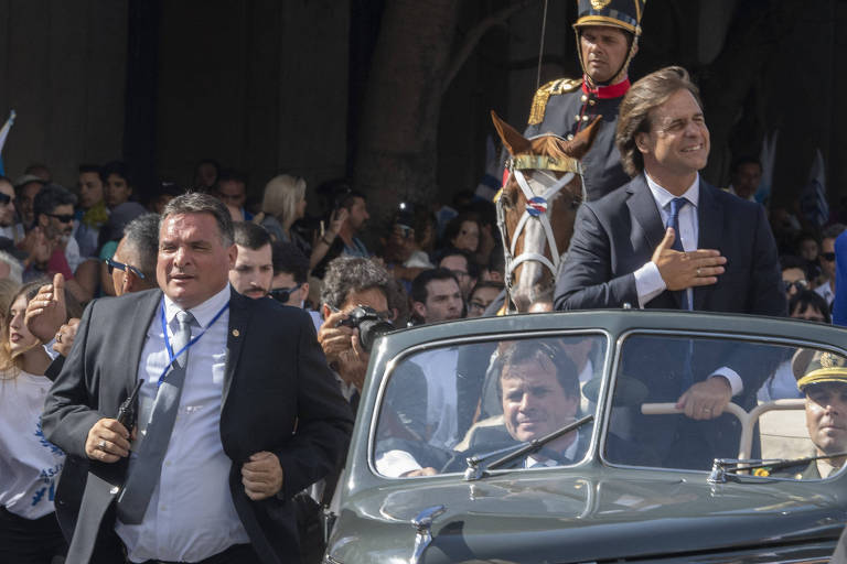 Alejandro Astesiano, então chefe de segurança da Presidência, corre ao lado de carro com Lacalle Pou na cerimônia de posse em Montevidéu