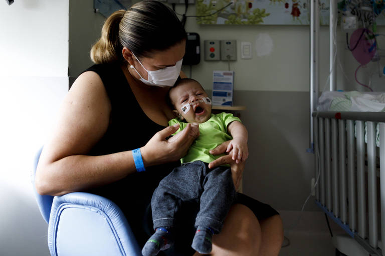 Na foto, mãe segura o bebê que está internado em enfermaria com bronquiolite causada por vírus sincicial respiratório, no hospital Sabará Infantil, em São Paulo