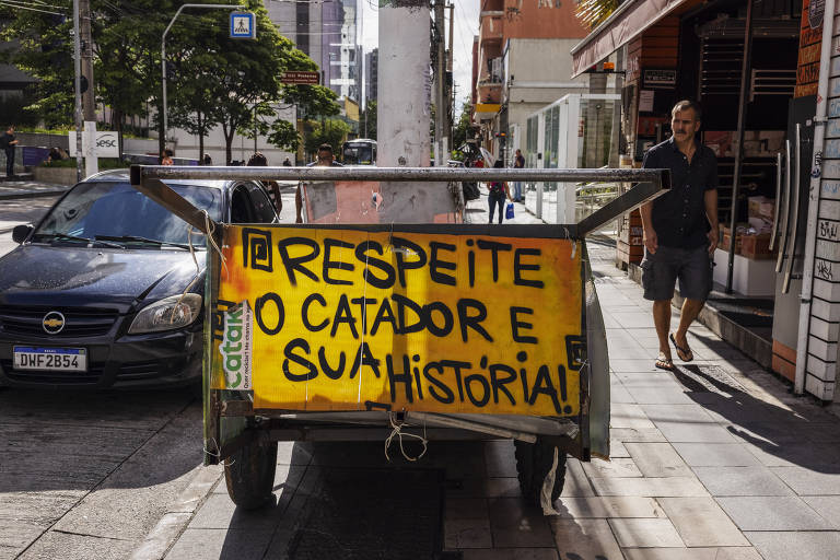 carroça em que se lê o cartaz em amarelo: respeite o catador e sua carroça