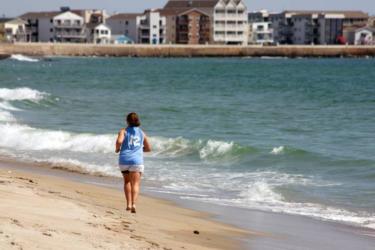 Mulher corre em areia da praia