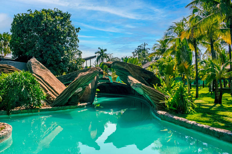 Cercado por coqueiros, um trecho do Obaaa River com replicas de cânions cobrindo as águas esverdeadas da piscina com correnteza